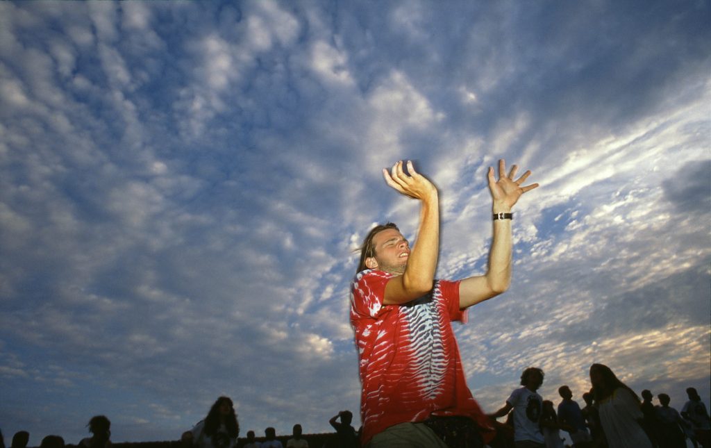 man holding hands up toward the sky at Grateful Dead Concert