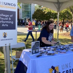 Arts Administration student Emilee Fann working the table at UNCG Homecoming 
