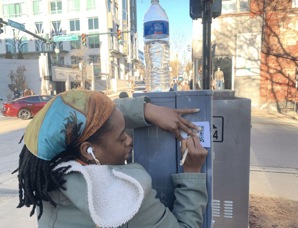 Student posting QR codes in Downtown Asheville