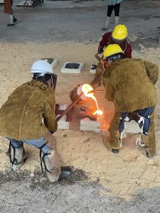 students pouring molten medal 