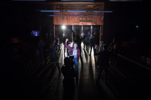 students onstage in dark with spotlight on one