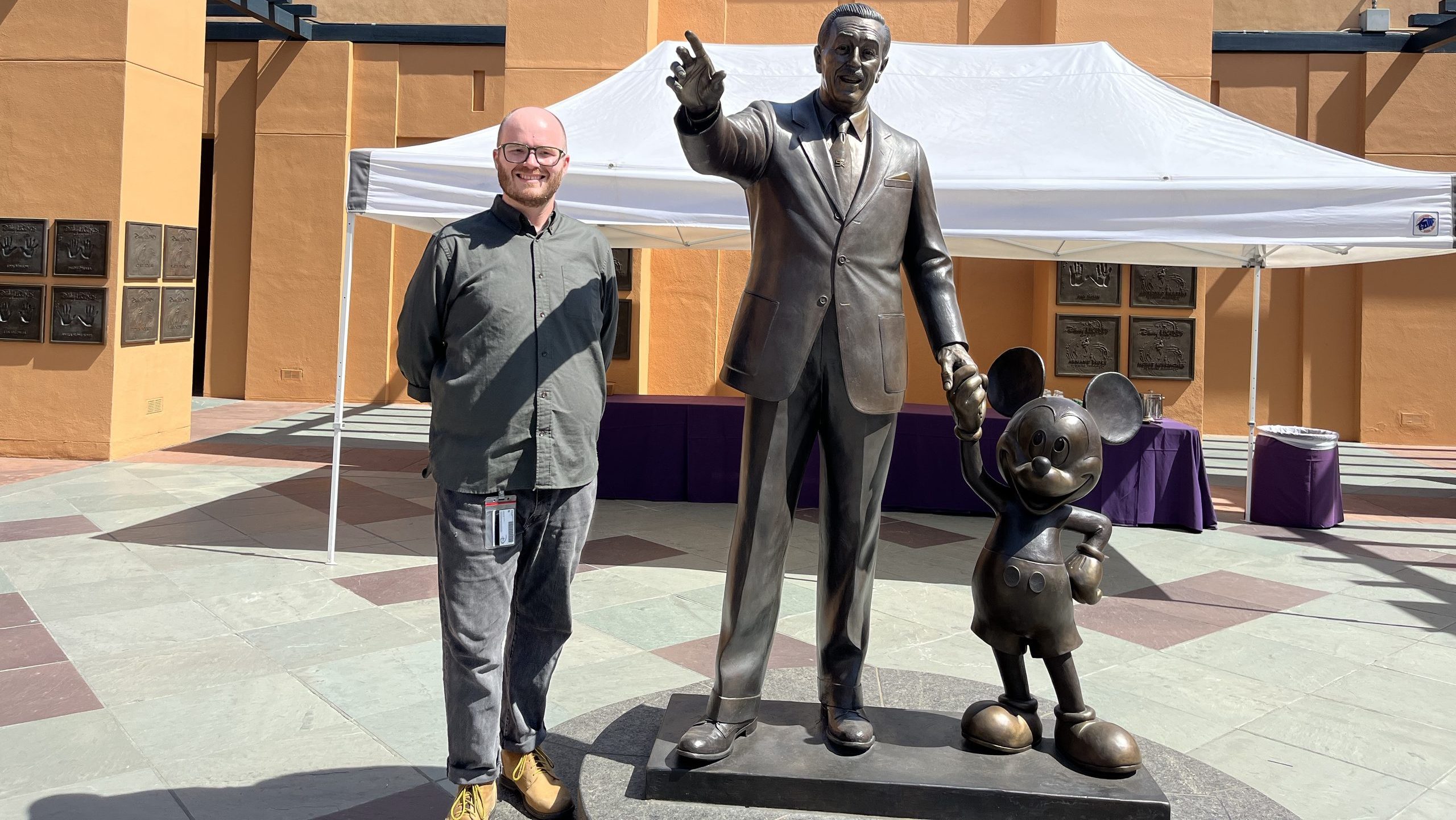 Theatre alum Max Kirkham with statue of Walt Disney and Mickey Mouse