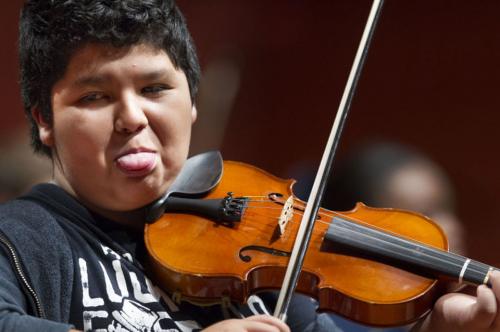 student sticks out tongue while playing violin
